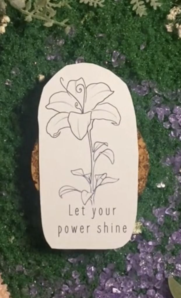 a sign that says let your power shine on the ground next to some grass and flowers