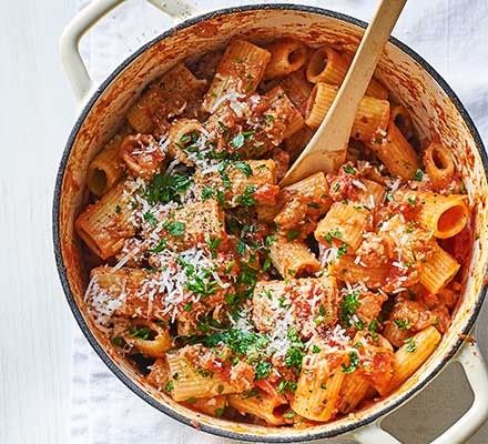 a pot filled with pasta and meat covered in parmesan cheese