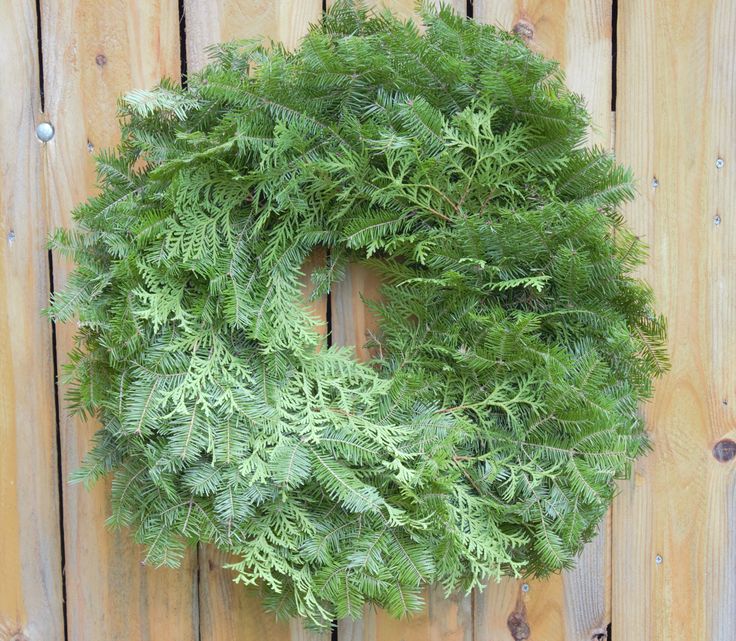 a green wreath hanging on a wooden fence