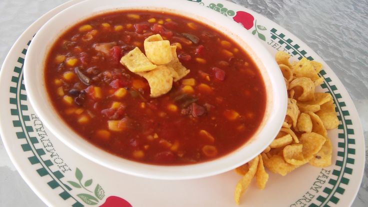 a bowl of chili and corn chips on a plate