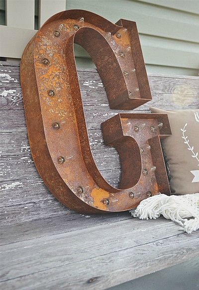 the number five is made out of rusted metal and sits on a wooden bench