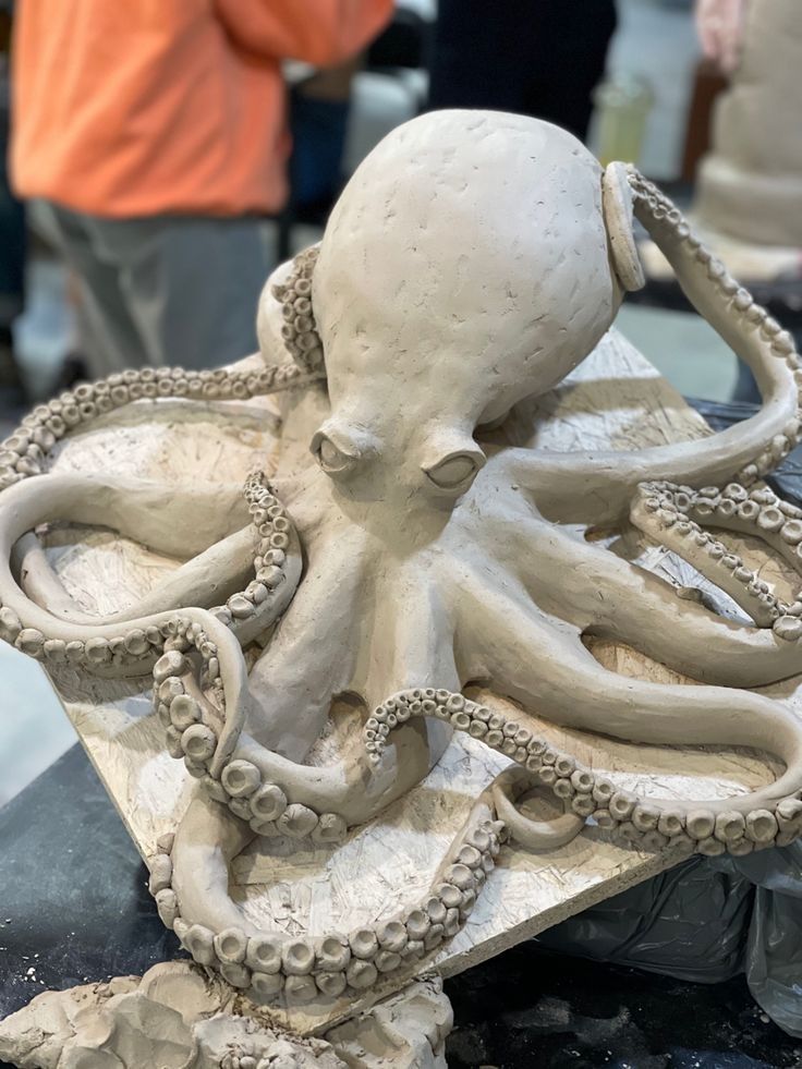 an octopus sculpture sitting on top of a table next to other people in the background