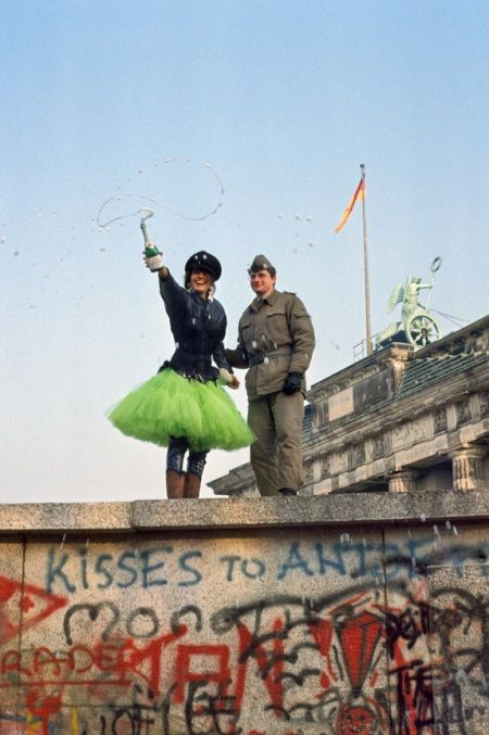 two people standing on top of a wall covered in graffiti