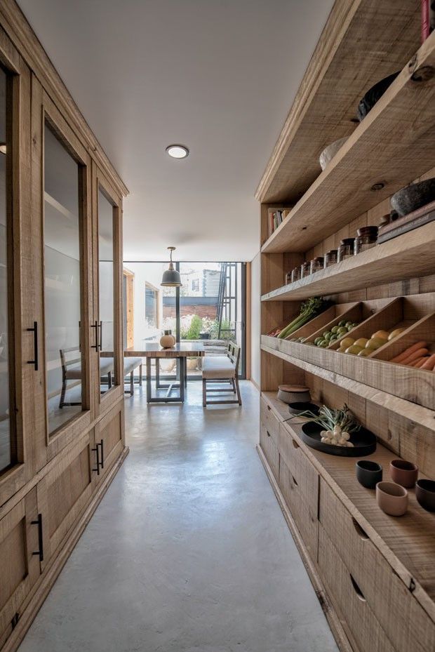 a long narrow hallway with wooden shelves filled with pots and plants