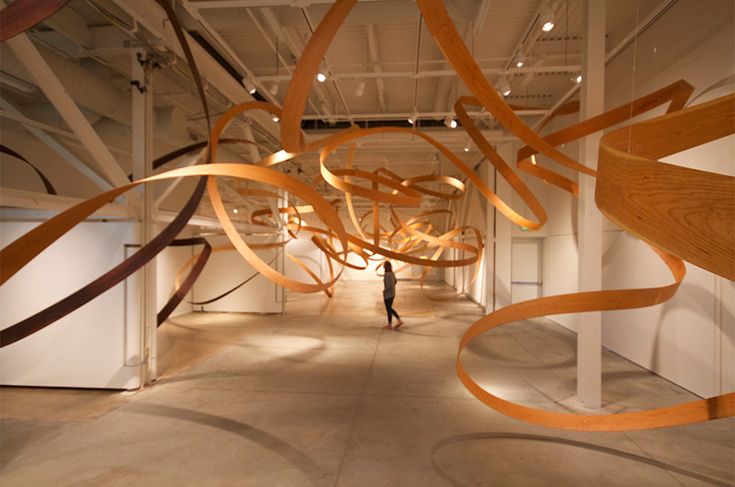 a person is walking through an art gallery with large wooden sculptures hanging from the ceiling