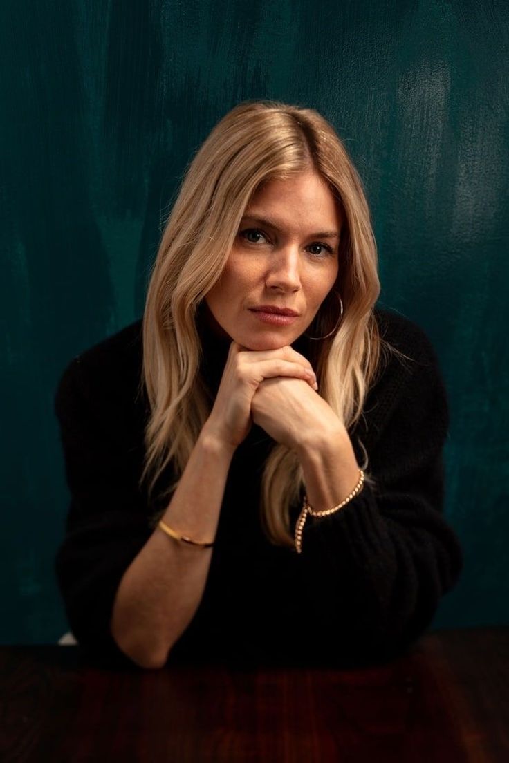 a woman sitting at a table with her hand on her chin and looking off to the side