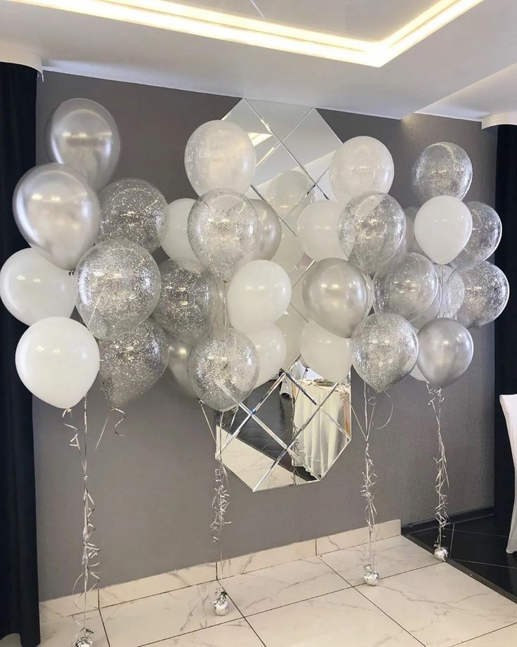 white and silver balloons are hanging from the ceiling