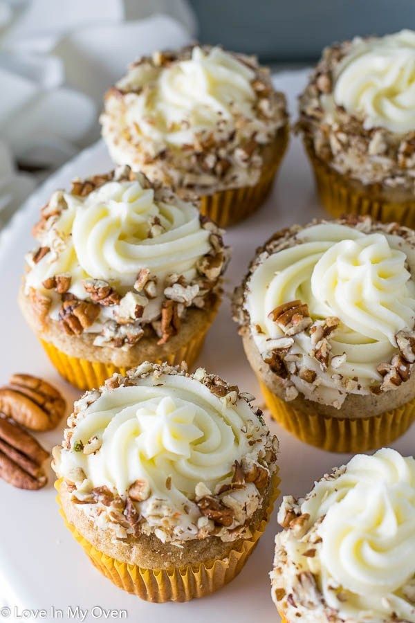 cupcakes with white frosting and pecans on a plate