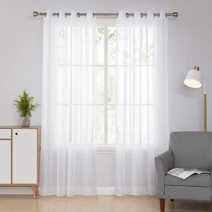 a living room with white curtains and a chair