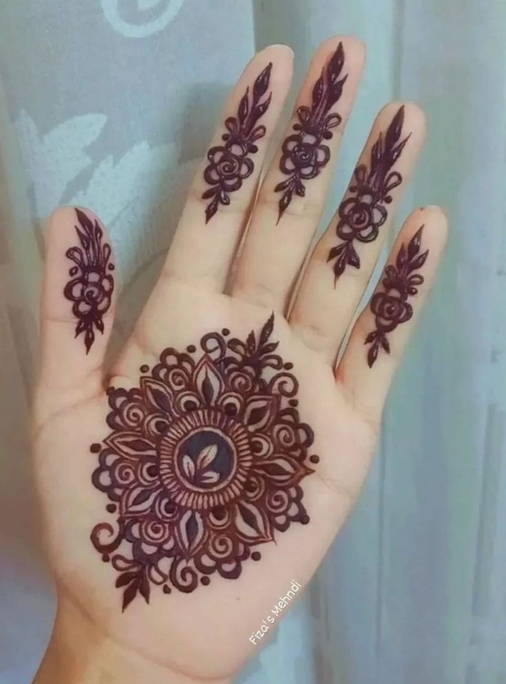 a hand with henna tattoos on it, and an intricate design in the middle