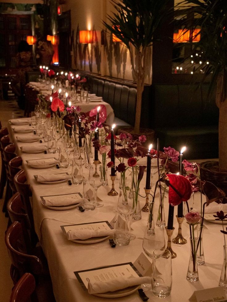 a long table is set with place settings and candles for the dinner guests to enjoy