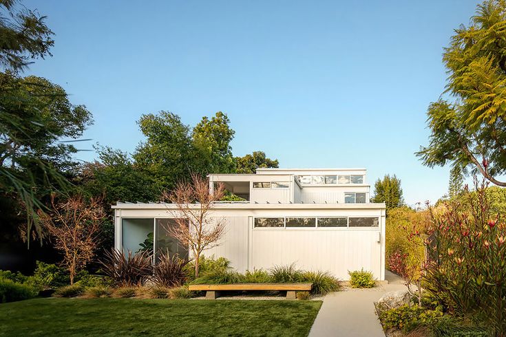 a white house sitting on top of a lush green field next to a tree filled forest