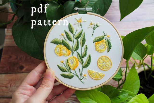 a person holding up a embroidery project with lemons on it