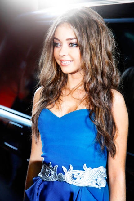 a beautiful young woman in a blue dress standing next to a car