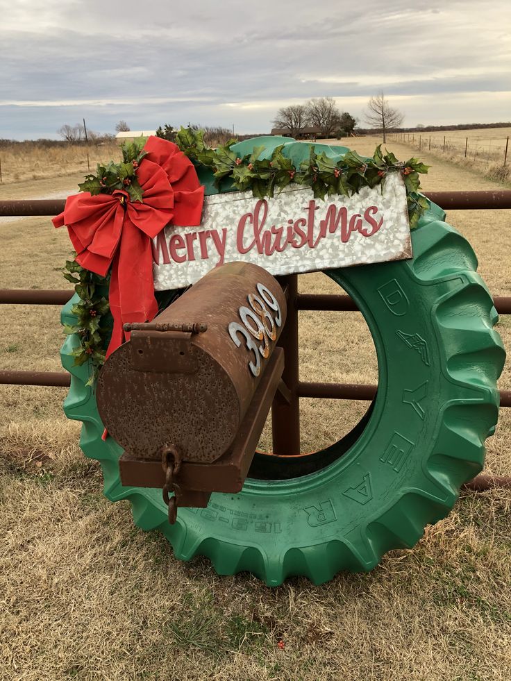 a tractor tire with a merry christmas sign on it's side in front of a fence