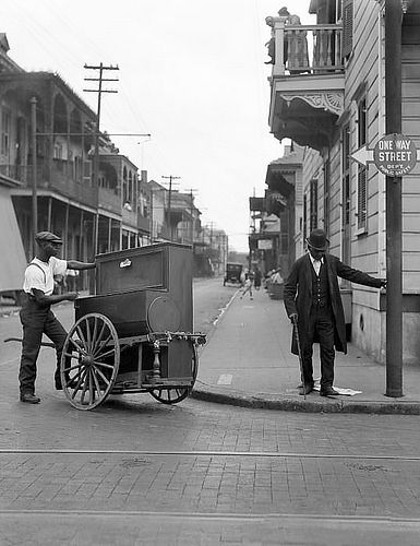 two men standing on the side of a street next to a horse drawn buggy