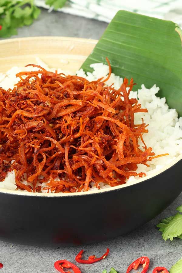 shredded red cabbage and white rice in a black bowl on a table with green leaves