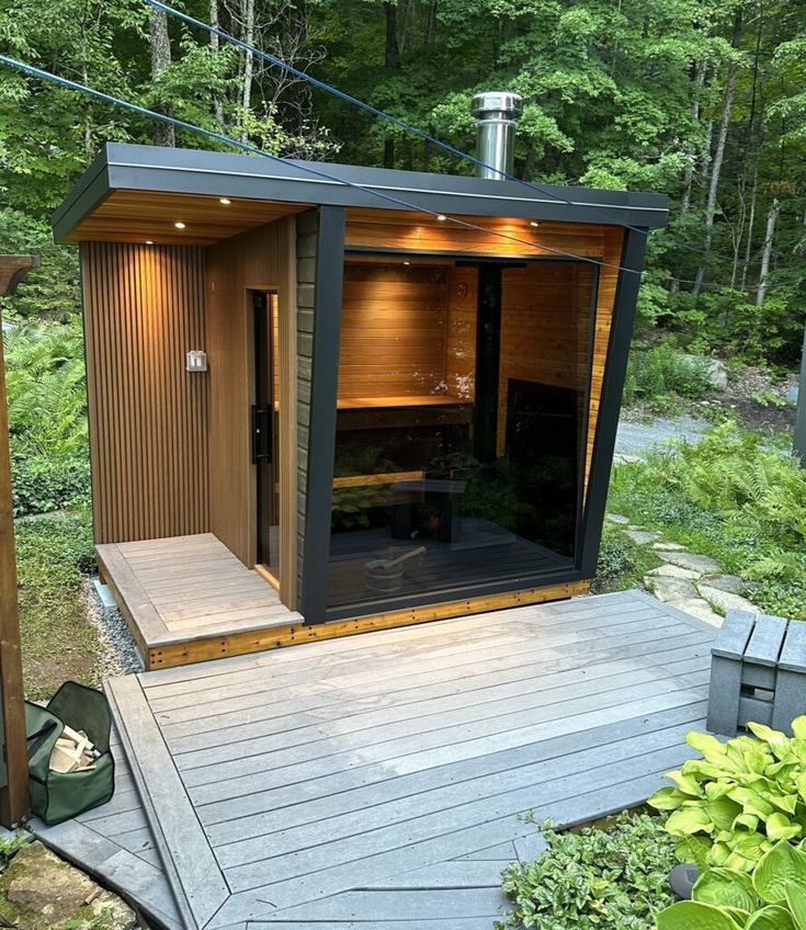 an outdoor sauna in the middle of a wooded area