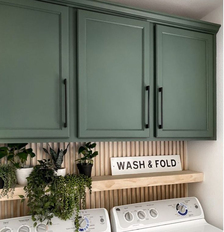 a washer and dryer sitting next to each other in a room with green cabinets