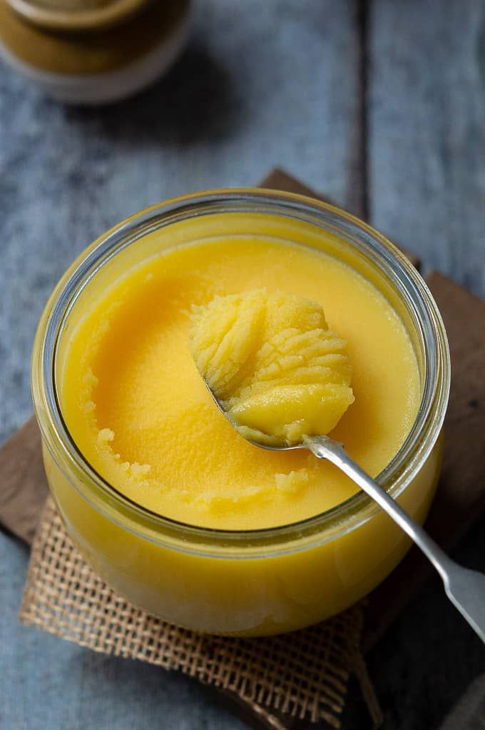 a glass jar filled with yellow liquid and a spoon