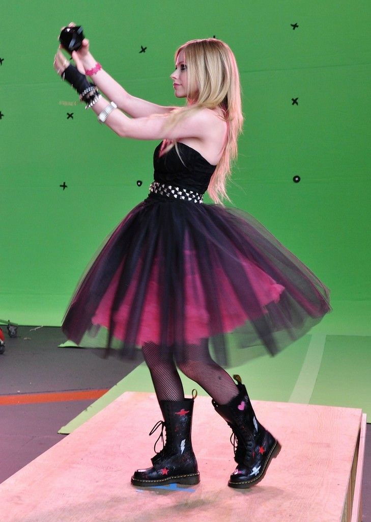 a woman in a black and pink dress is holding a camera while standing on a stage