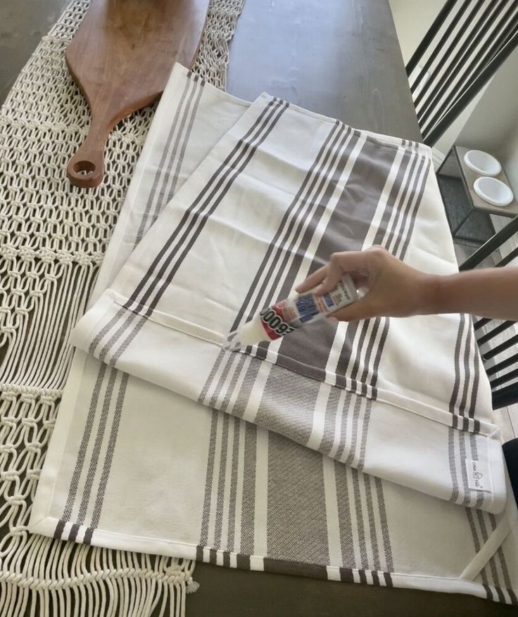 a person is using a brush to paint the table cloths on top of each other