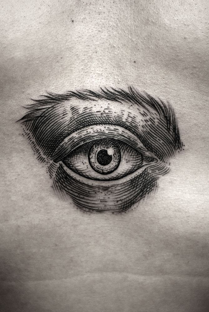 an eye tattoo on the side of a man's chest is shown in black and white