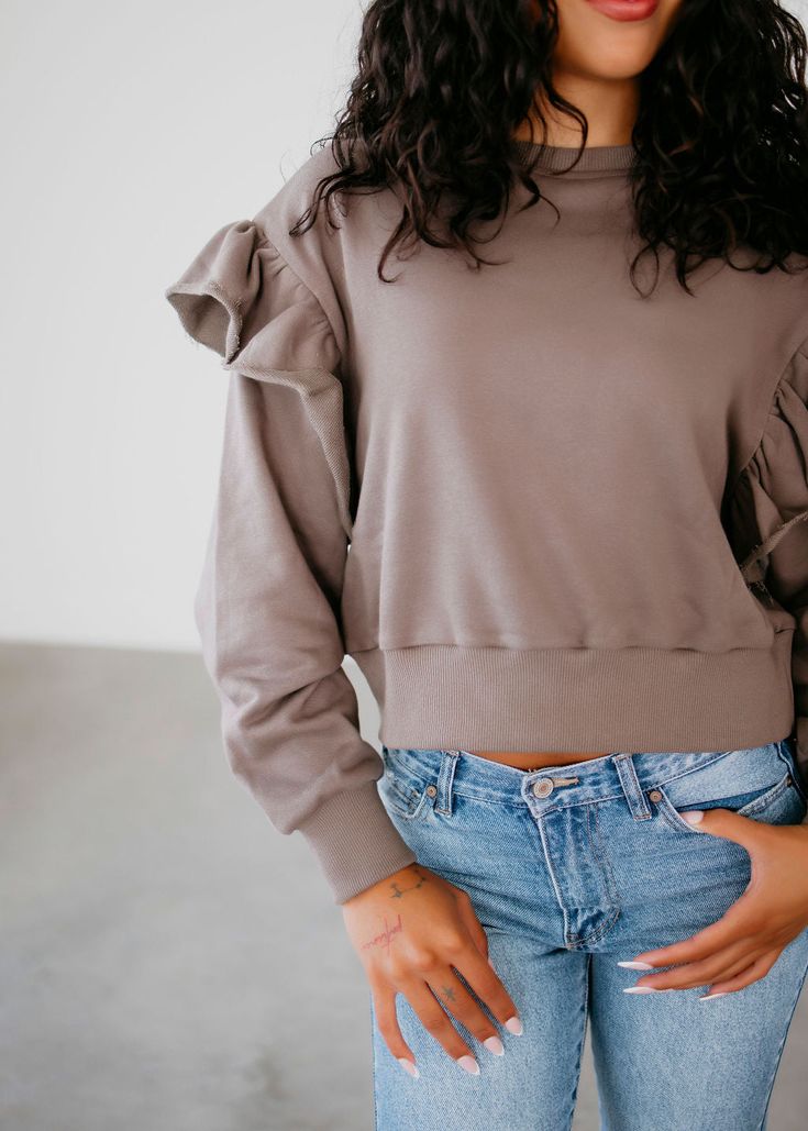 Effortlessly elevate your casual look with our Sienna Ruffled Detail Sweatshirt. The ruffle detail on the sleeves adds a touch of femininity, while the relaxed fit and banded waistband provide comfort and style. With long sleeves, banded cuffs, and a mock neck, this sweatshirt is perfect for any occasion. Serenity is wearing a size small. Measurements: Body Length: 20.75" | Sleeve Length: 23" Small: Bust: 42" Arm: 19" Medium: Bust: 44" Arm: 19" Large: Bust: 46" Arm: 20" 100% Cotton Taupe Tops For Fall Day Out, Taupe Tops For Day Out In Fall, Taupe Tops For A Fall Day Out, Spring Cotton Ruffled Sweatshirt, Spring Cotton Ruffle Sweatshirt, Spring Cotton Sweatshirt With Ruffles, Chic Spring Sweatshirt For Layering, Trendy Relaxed Fit Top With Ruffle Sleeves, Trendy Tops With Relaxed Fit And Ruffle Sleeves