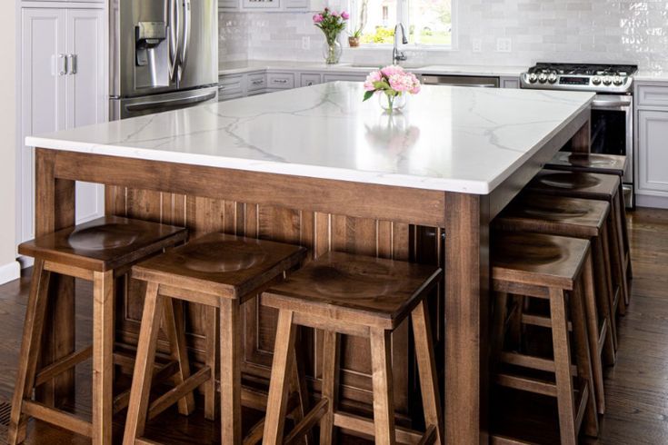 a kitchen island with four stools in front of it and an oven on the other side