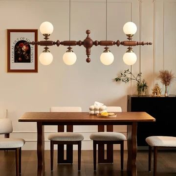 a dining room table and chairs with lights hanging from it's ceiling above them