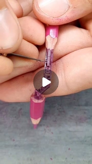 someone is holding a pink pencil with a hole in it