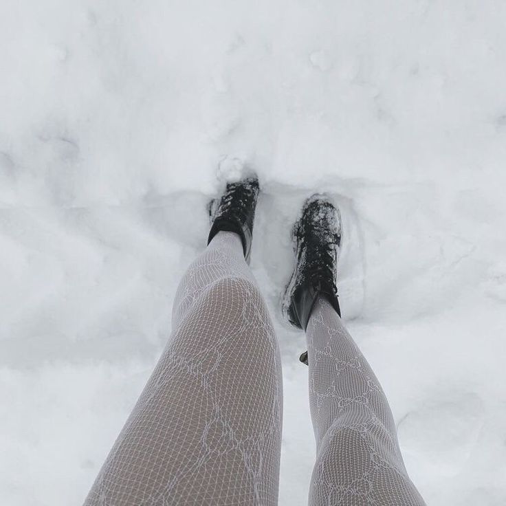 the legs and feet of a woman in fishnet stockings are seen from above as she stands on snow - covered ground