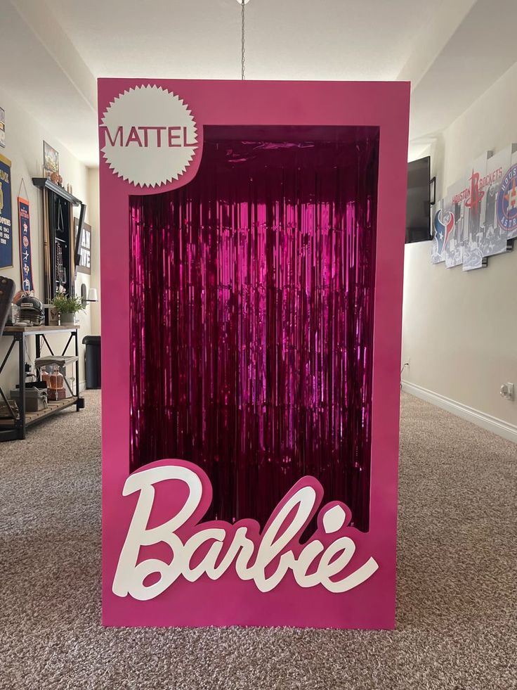 a pink box with the word barbie on it in front of a carpeted hallway