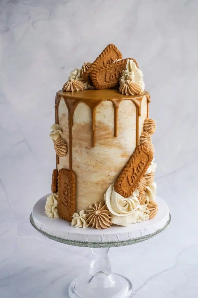 a cake with icing and cookies on top is sitting on a plate in front of a marble background