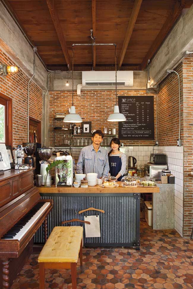 a man and woman standing in front of a piano at a counter with food on it