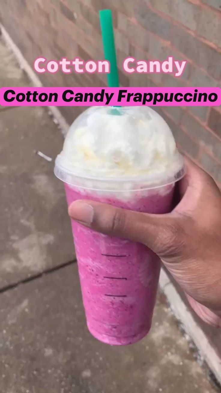 a hand holding up a purple cup with whipped cream