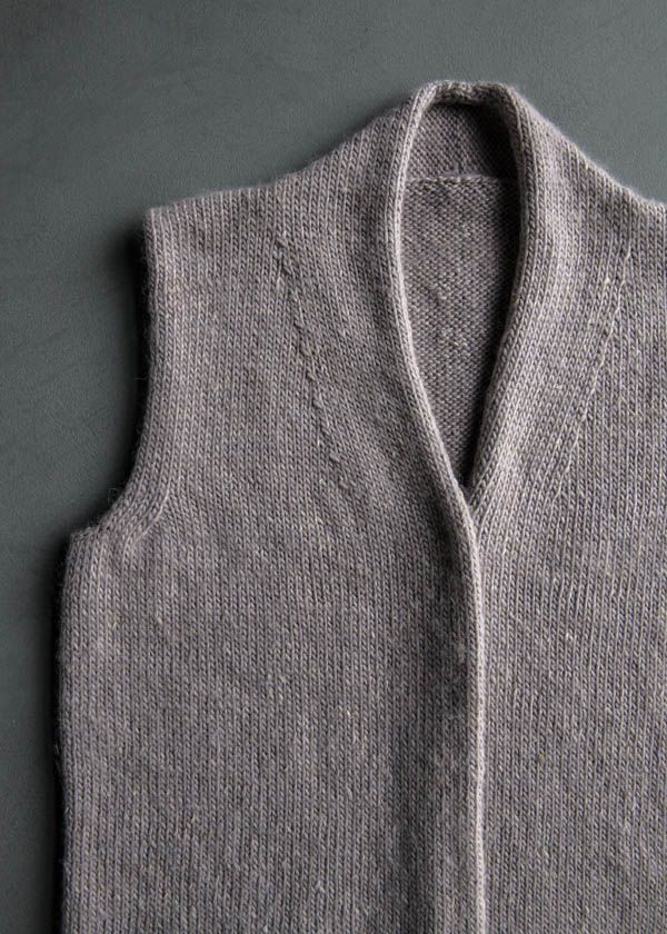 a gray sweater vest sitting on top of a table