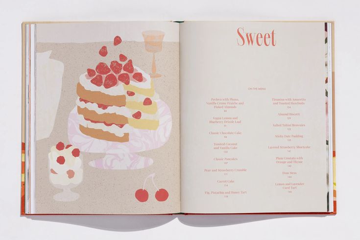 an open cookbook with a cake and dessert on the cover, in front of a white background