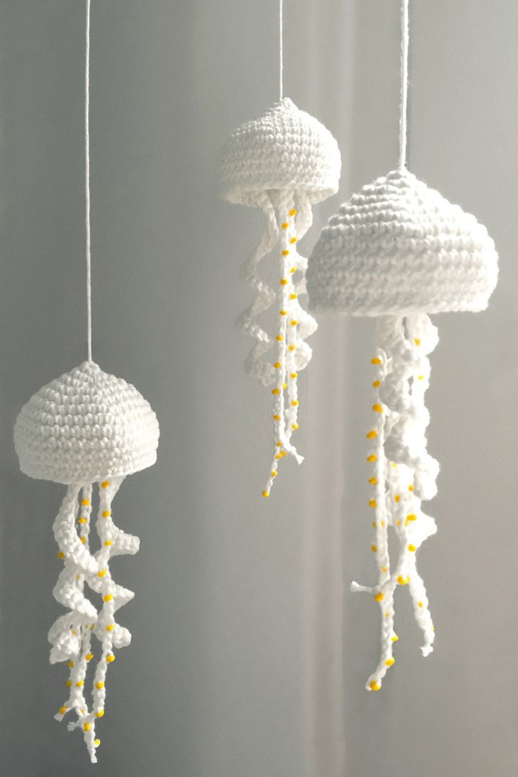 three crocheted jellyfish mobiles hanging from strings in white and yellow colors