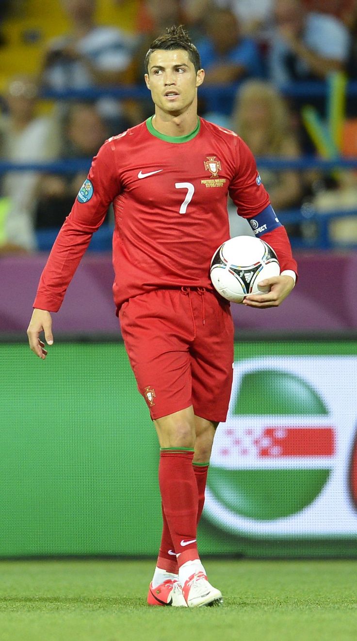 a soccer player is holding a ball in his hand and walking on the field during a game