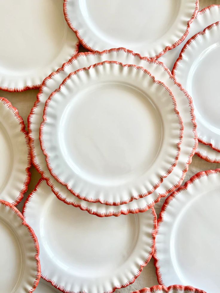 many white plates with red ruffled edges are stacked on top of each other