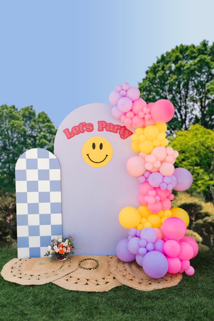 a balloon arch with a smiley face on it and some balloons in the shape of a tombstone