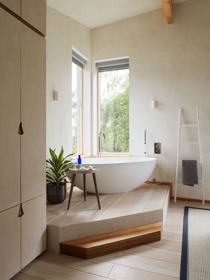 a bath tub sitting next to a window on top of a hard wood flooring