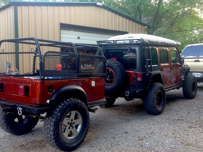 two jeeps are parked next to each other in front of a building with a garage