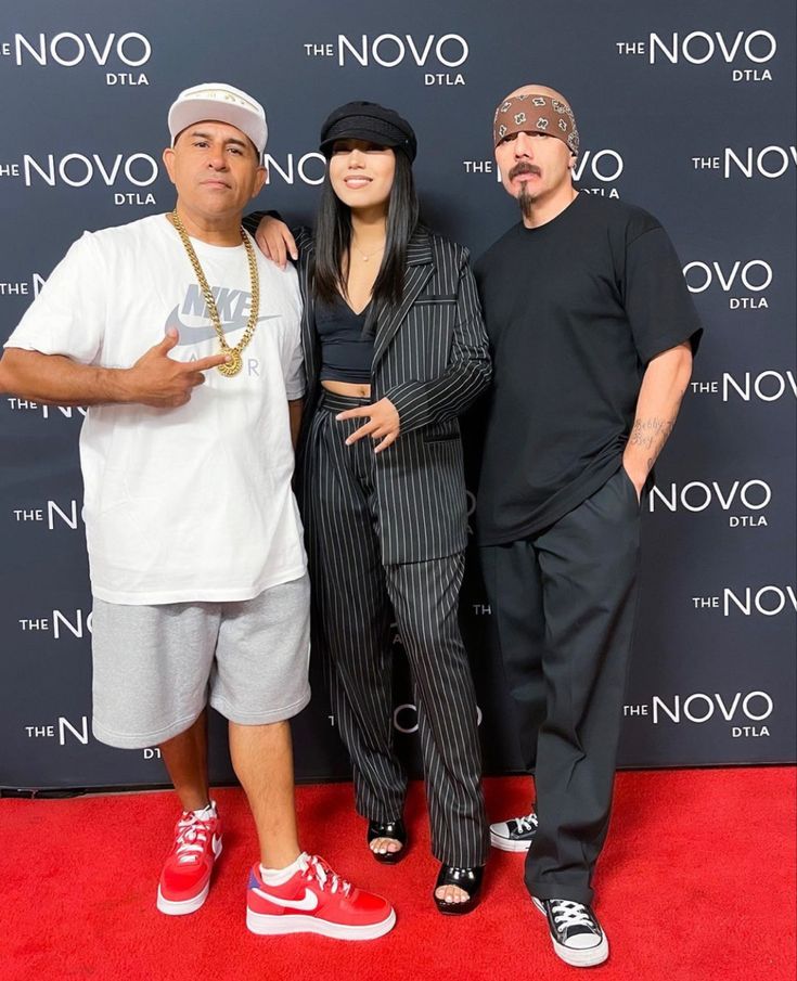 three people standing next to each other on a red carpet