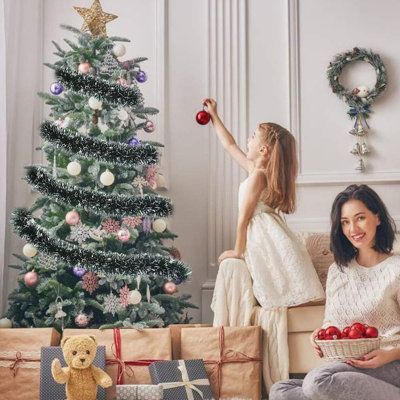 two women sitting on a couch in front of a christmas tree with presents under it