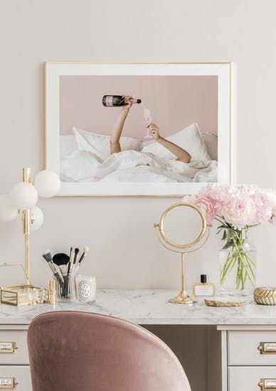 a white desk topped with a pink chair next to a mirror and vase filled with flowers