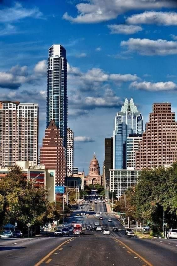 a city street with tall buildings in the background