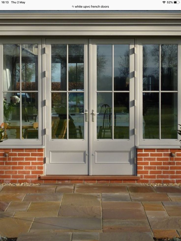 a brick building with two doors and windows on each side, in front of a patio area