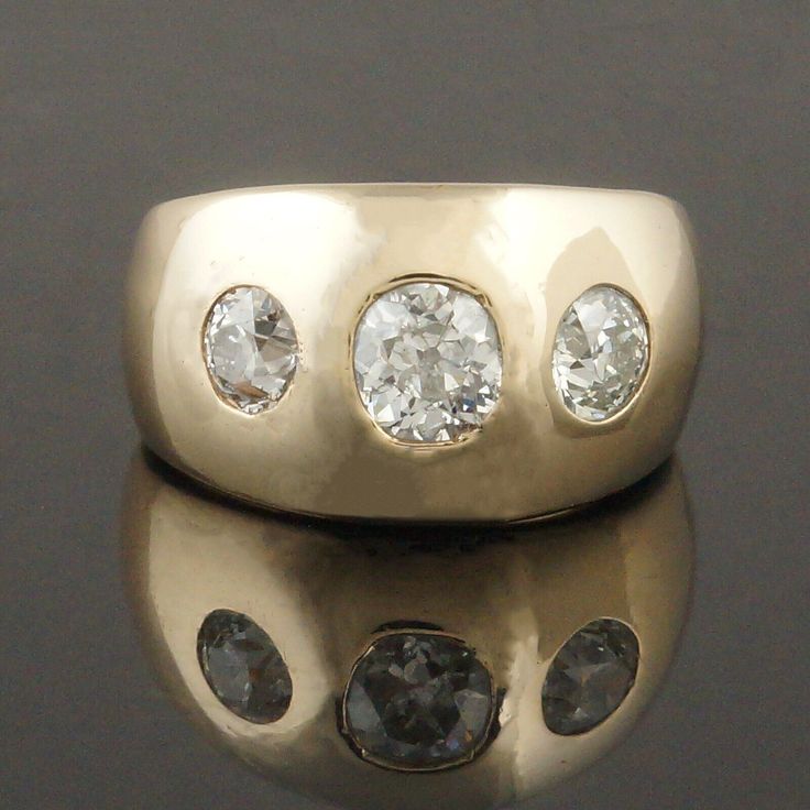 three stone ring sitting on top of a reflective surface